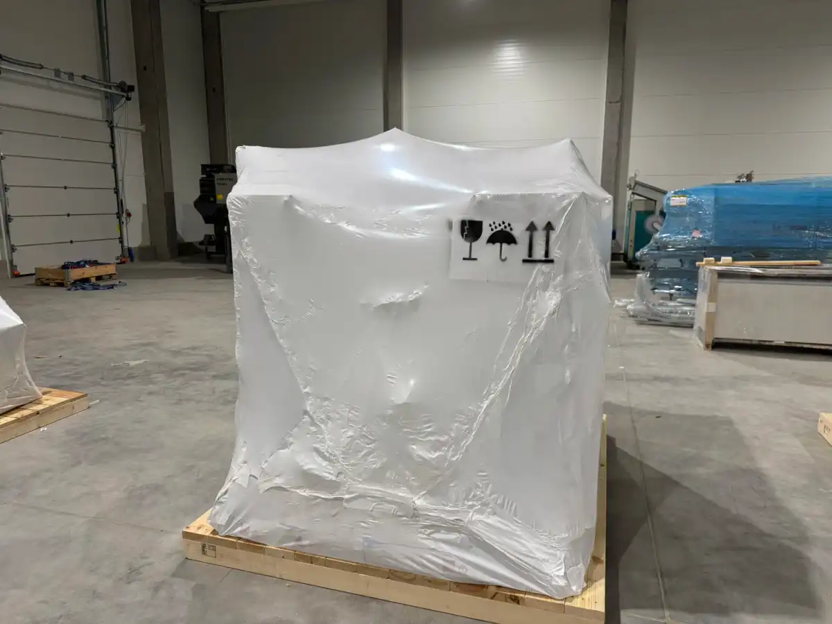 Maszyna opakowana w napiętą, białą folię termokurczliwą na samochodzie ciężarowym